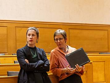 Zwei Stadtratsmitglieder lauschen stehend einem Votum im Rat