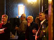 Gäste stehend mit Glas blicken auf die Bühne