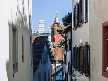 Blick durch eine Gasse der Altstadt mit dem Rathaus und dem Roche-Tower im Hintergrund