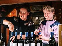 Zwei Mitarbeitende der «Heitere Fahne» öffnen lachend Weinflaschen.